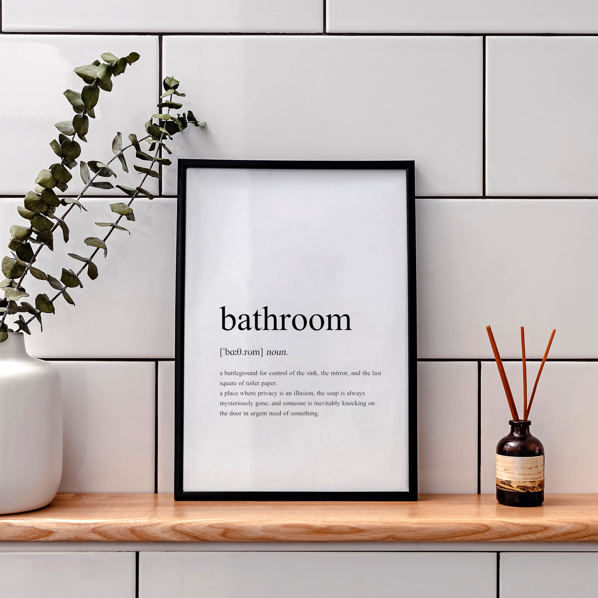 Single portrait typography print featuring a dictionary-style definition of the word bathroom. The word itself, together with its phonetic pronunciation, type and definition are included. Text is in a lower case serif font, black on a white background and left-aligned.
