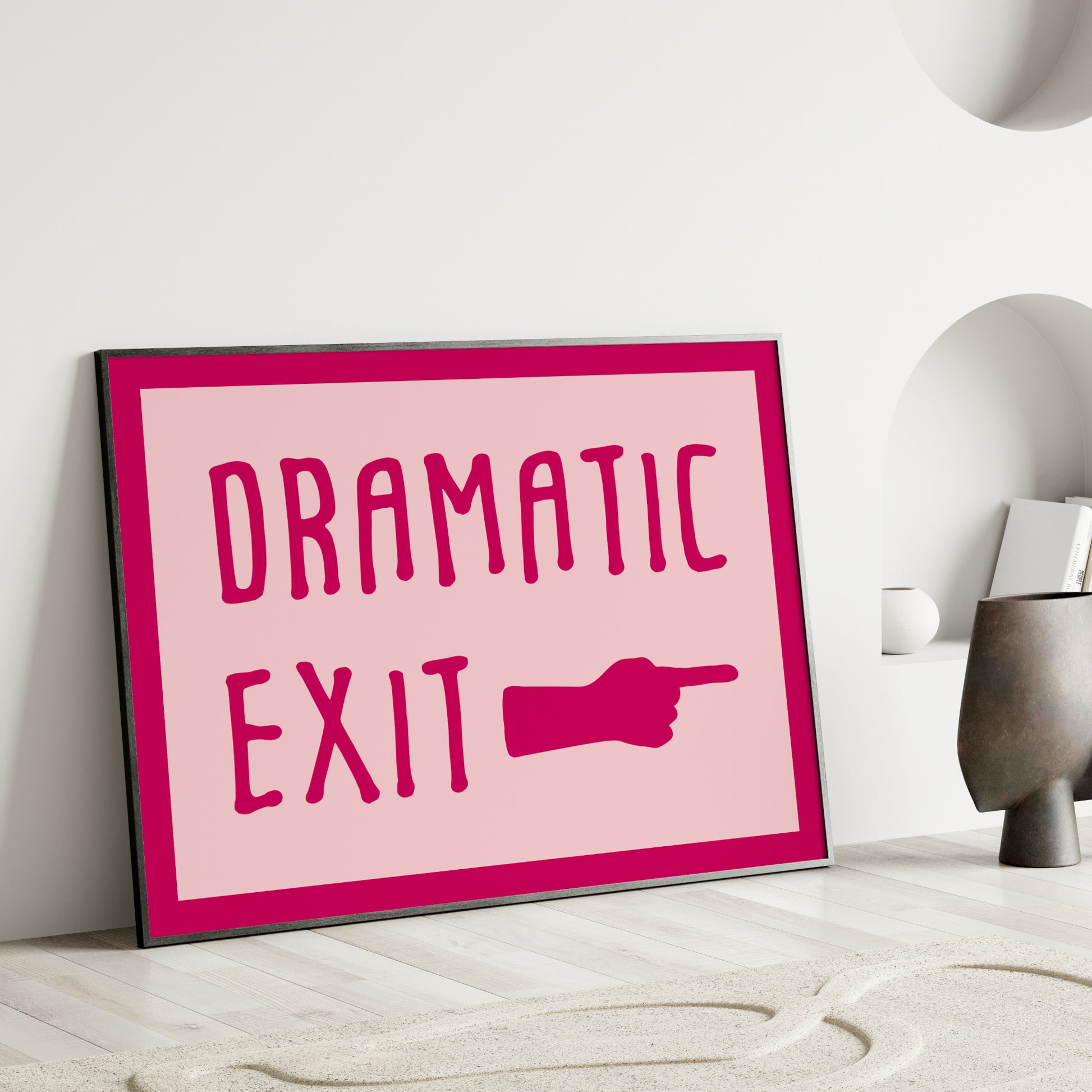 Single landscape print featuring the text "Dramatic exit" next to a hand with a pointed finger. Text is in a playful upper case font, darp pink on a pale pink background. There is also a dark pink border. Styling is retro and fun.