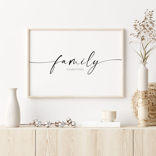 Single landscape typography print. Text reads: family is everything. The word "family" is positioned prominently in an elegant script font, with trailing ends to the lead and end letters, extending to the edges of the print. The remining text is in a crisp upper case sans serif font. Text is centre-aligned and black on a white background.