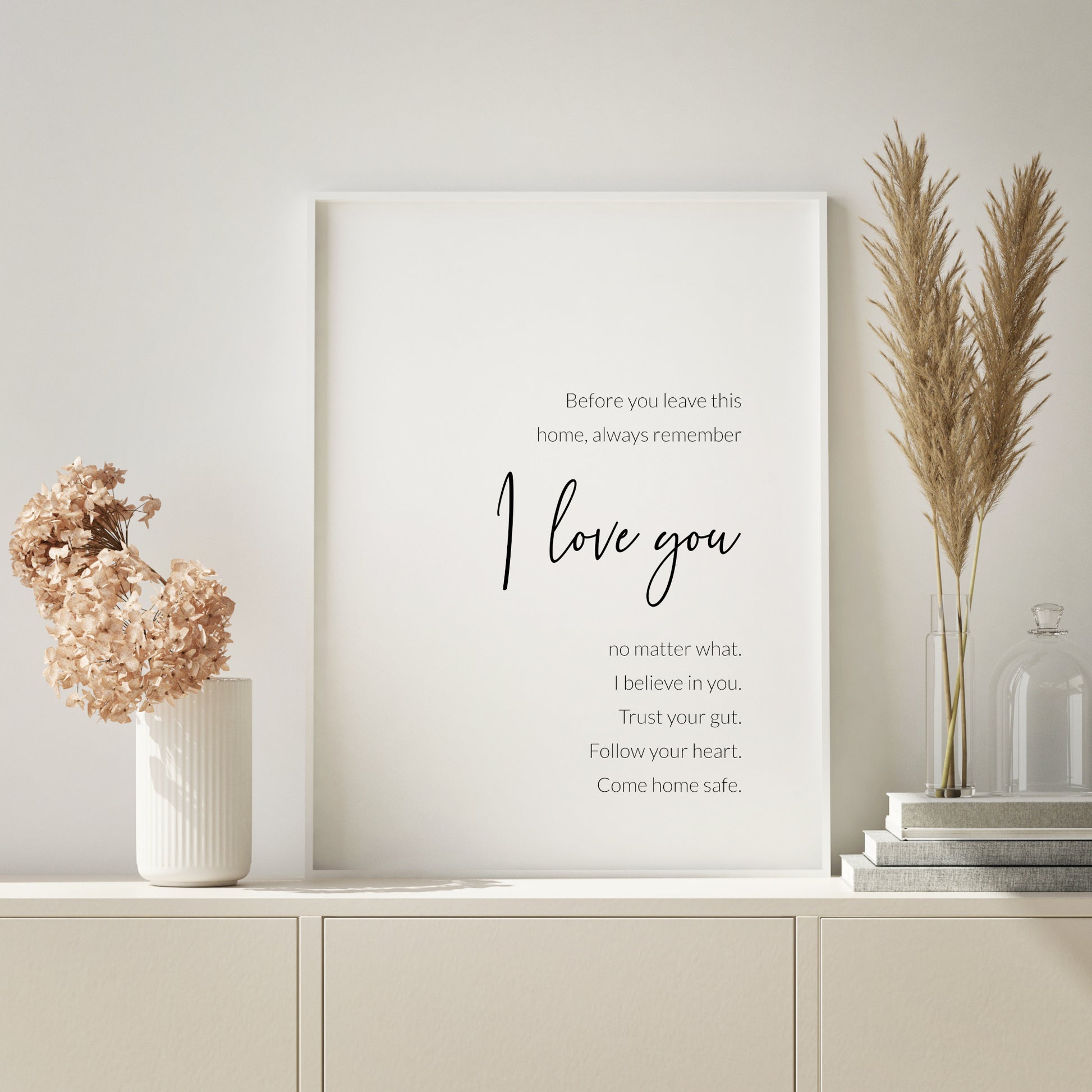 Single portrait typography print. Text reads: Before you leave this home, always remember I love you no matter what. I believe in you. Trust your gut. Follow your heart. Come home safe. The words I Love You are positioned prominently in a modern script font. Remaining text is in a lightweight sans serif font. All text is black on a white background and right-aligned. Styling is contemporary and elegant.