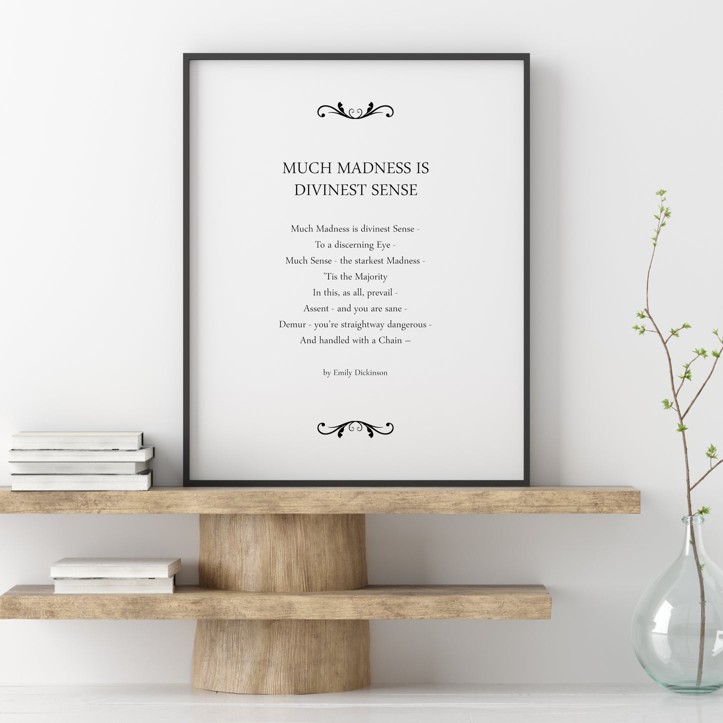 Single portrait typography print featuring the poem Much Madness Is Divine Sense by Emily Dickinson. Text is in a classically styles serif font, with the title in upper case and the body and attribution below in sentence case, but respecting incidental capitalisation of the original. All text is centre-aligned, and is black on a white background. A filigree ornament frames the text top and bottom. Styling is classic and elegant.