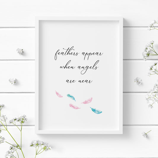 Single portrait typography print. Text reads: feathers appear when angels are near. All text is in lower case and in an elegant script font. Several pale pink and blue feather are positioned below the text. Text is black on a white background.