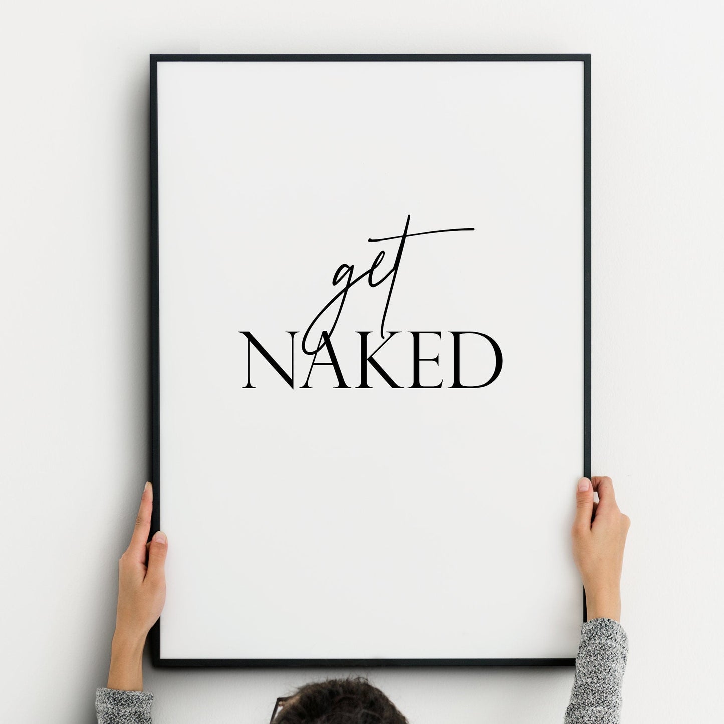 Single portrait typography print shown in a bathroom setting. Quote reads: get naked. The word "get" is in a stylish script font, contrasting with the upper case serif font used for the word "naked". Text is black on a white background.