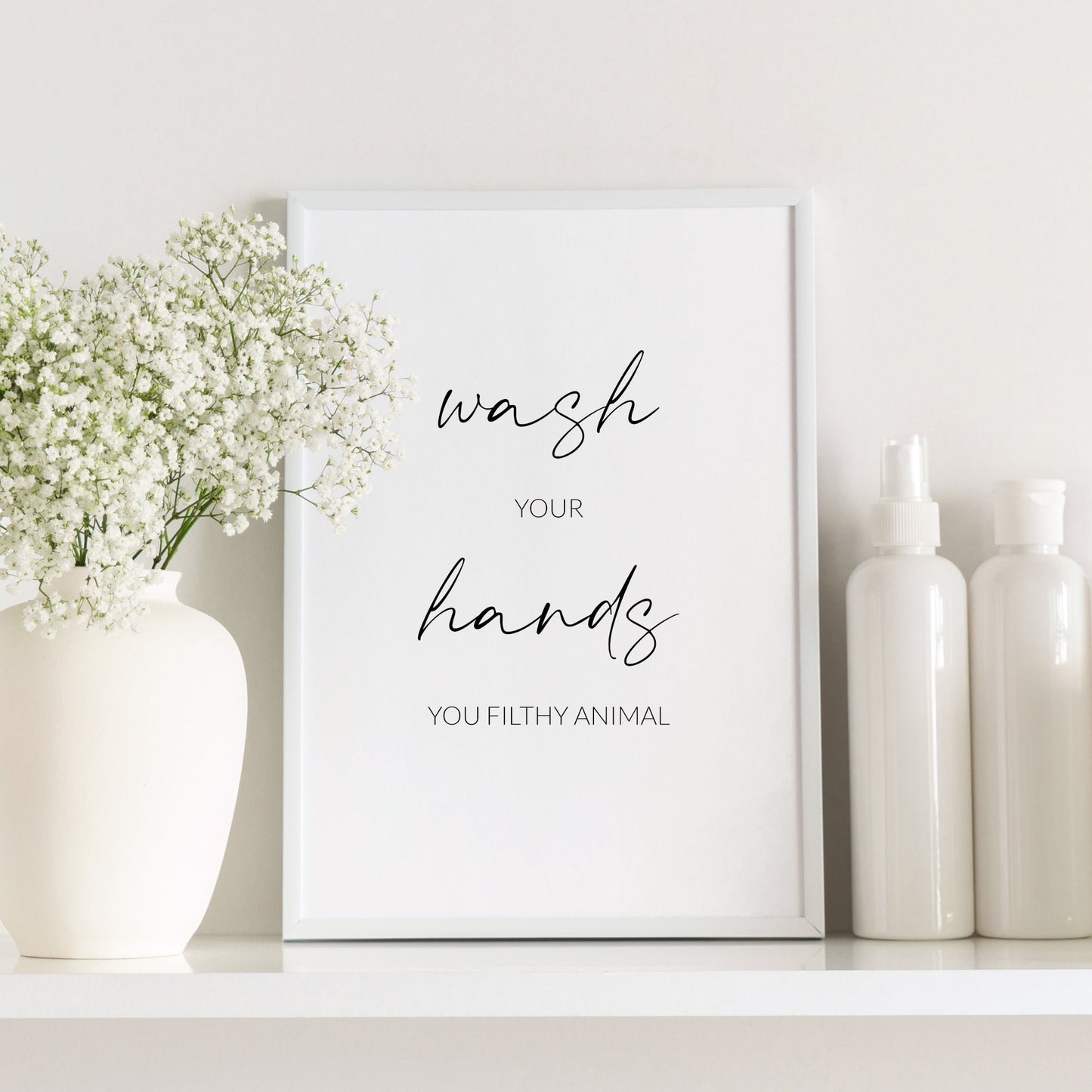 Single portrait typography print shown in a bathroom setting. Text reads: Wash your hands you filthy animal. The words wash and hands are displayed prominently in an elegant script font.