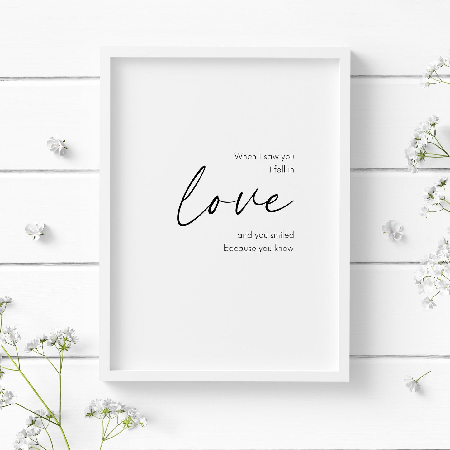 Romantic typography print, with the quote: When I saw you I fell in love and you smiled because you knew. The word love is displayed prominently in an elegant script font. Orientation is portrait and text is black on a white background.