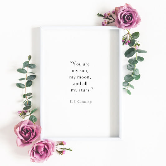 Single portrait typography print shown in a romantic setting. Text reads: "You are my sun, my moon, and all of my stars". This is followed by an attribution to E. E. Cummings.. Text is in an elegant sans serif font, black on a white background.
