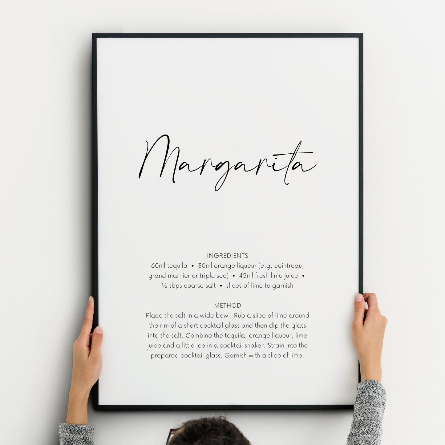 Single portrait print featuring the recipe and instructions for a margarita cocktail. The word margarita is positioned prominently in a script font, with the remaining text shown in a crisp sans serif font below. Text is black on a white background.