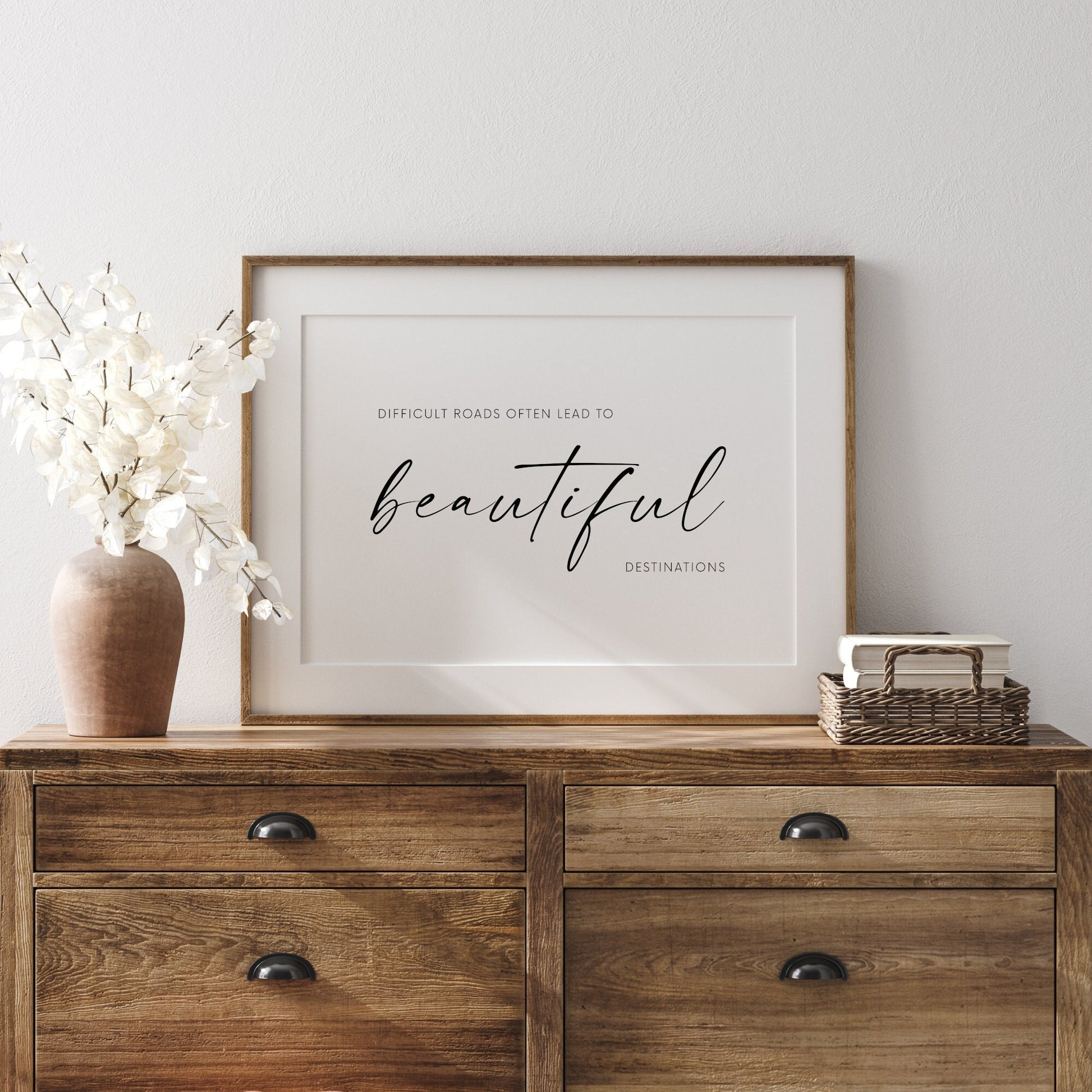 Single landscape typography print. Quote reads: Difficult roads often lead to beautiful destinations. The word beautiful is placed prominently in an elegant script font. Other text is in a crisp sans serif font. Text is white on a black background.