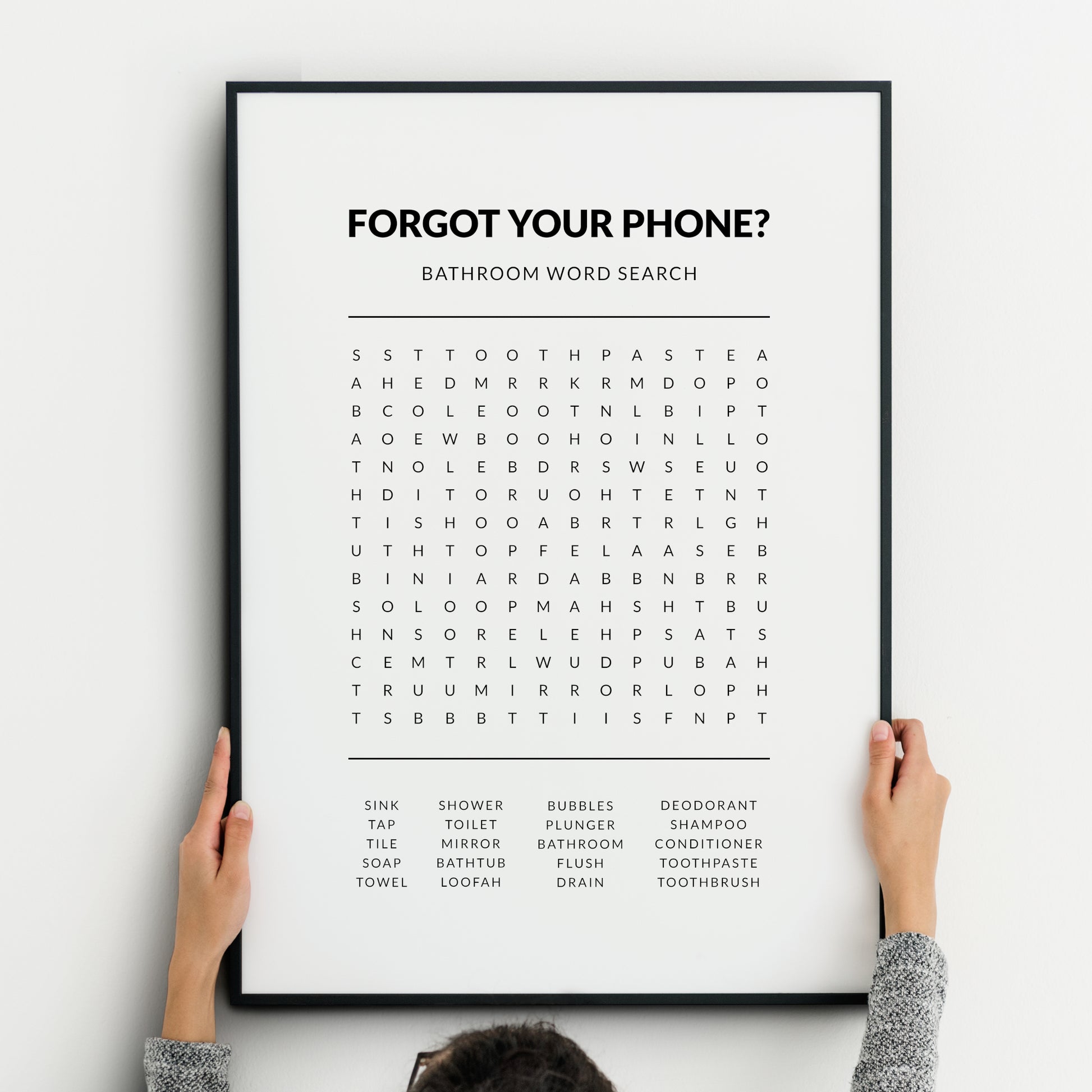 Bathroom word search print featuring the heading “Forgot your phone?” with a grid puzzle and a list of bathroom-related words below, presented in clean black typography on a white background.