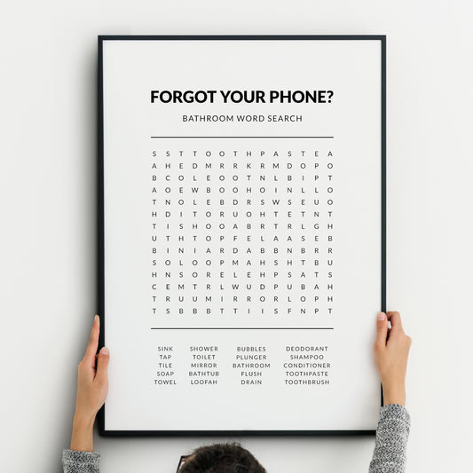 Bathroom word search print featuring the heading “Forgot your phone?” with a grid puzzle and a list of bathroom-related words below, presented in clean black typography on a white background.