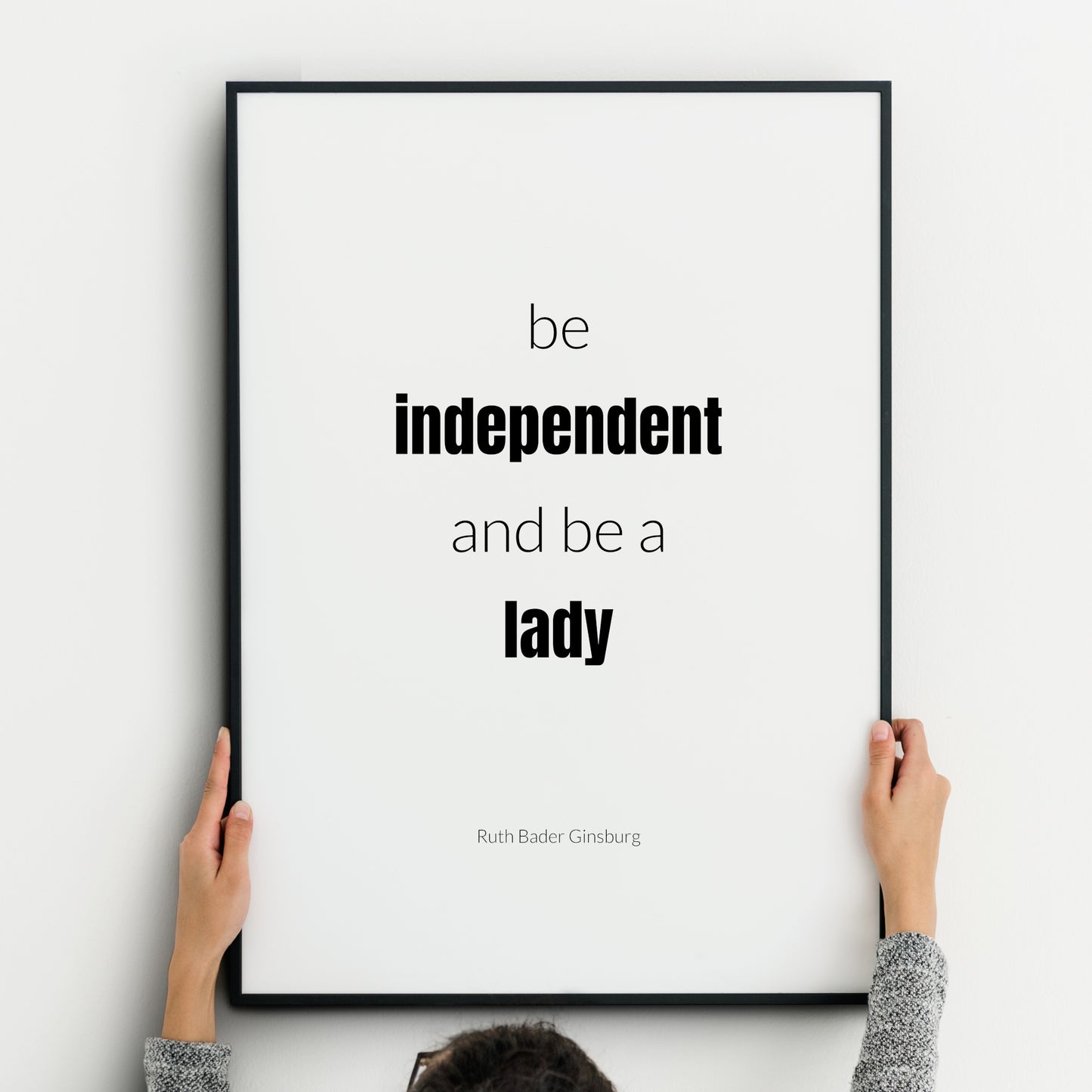 Single portrait typography print. Text reads: Be independent and be a lady. An attribution to Ruth Bader Ginsburg is below. "Independent lady" is highlighted in bold. Text is in a lower case sans serif font, black on a white background.