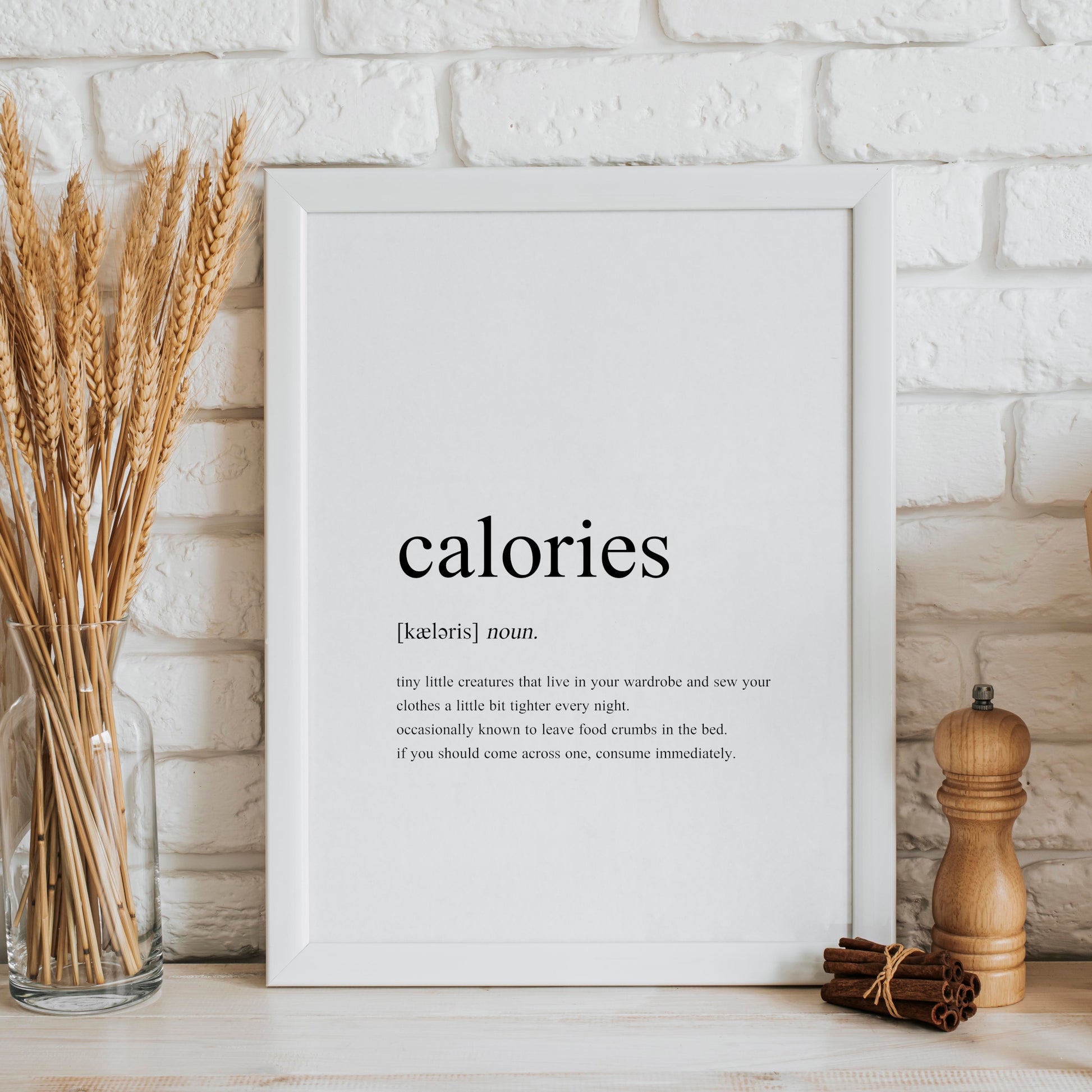 Single portrait typography print showing a humorous definition of the word calories in a traditional dictionary-style. Text is black on a white background.
