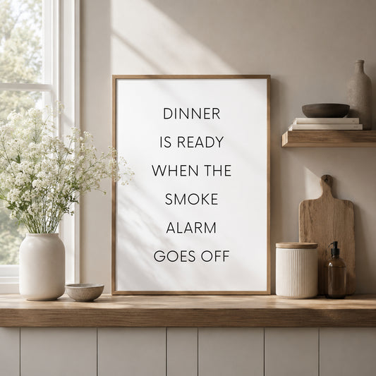 Single portrait typography print featuring the quote: Dinner is ready when the smoke alarm goes off. Text is in a modern upper case sans serif font. Text is black on a white background.