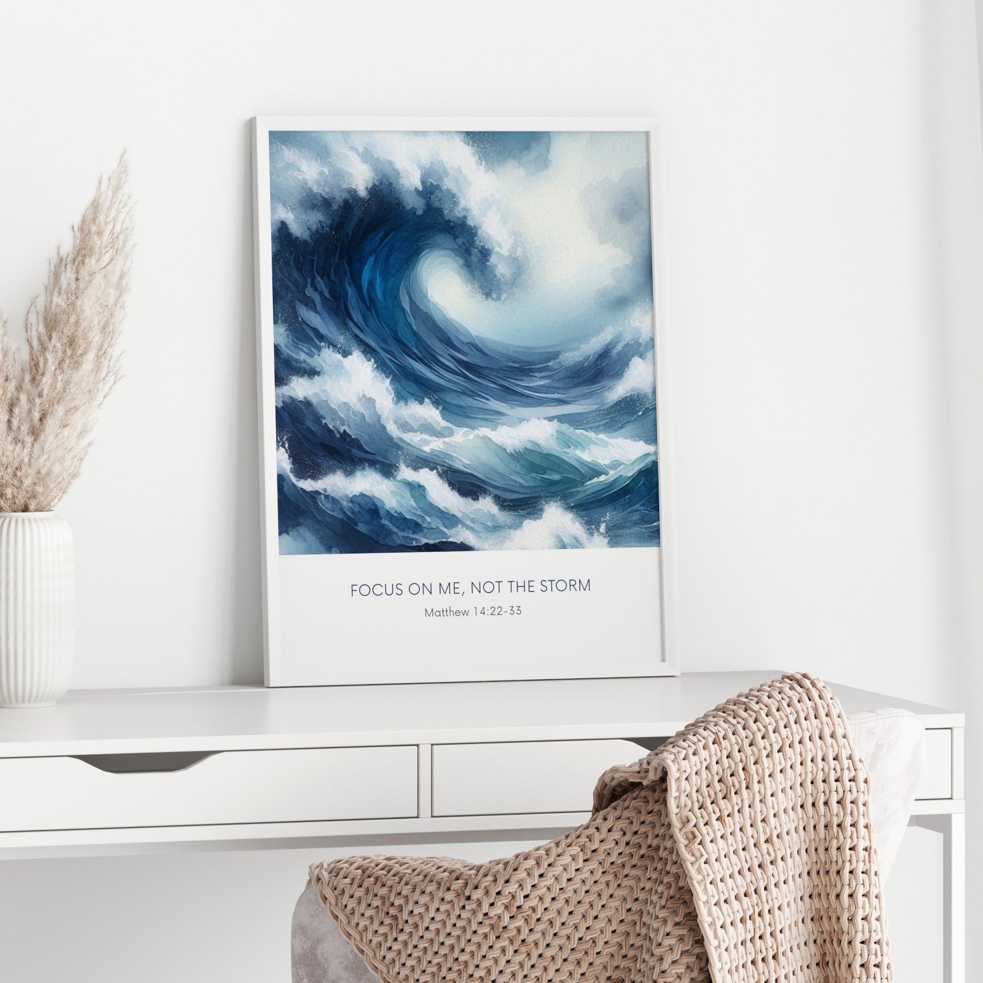 Single portrait illustrated print. Illustration is of a stormy sea showing a large crashing way in moody shades of blue and white. A bible verse is positioned below, reading: Focus on me, not the storm. An attribution to Matthew 14:22-33 is positioned below that again. All text is centre-aligned and in a sans serif font. Text is dark blue on a white background. Styling is contemporary and elegant.