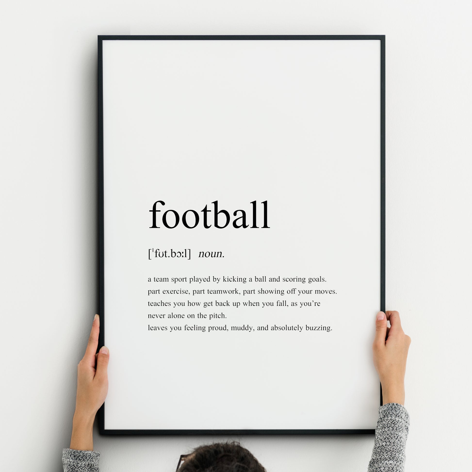 Single portrait typography print featuring a dictionary style definition of the word Football. It includes the word itself, its pronunciation, word type and then the definition. All text is black on a white background and left-aligned.