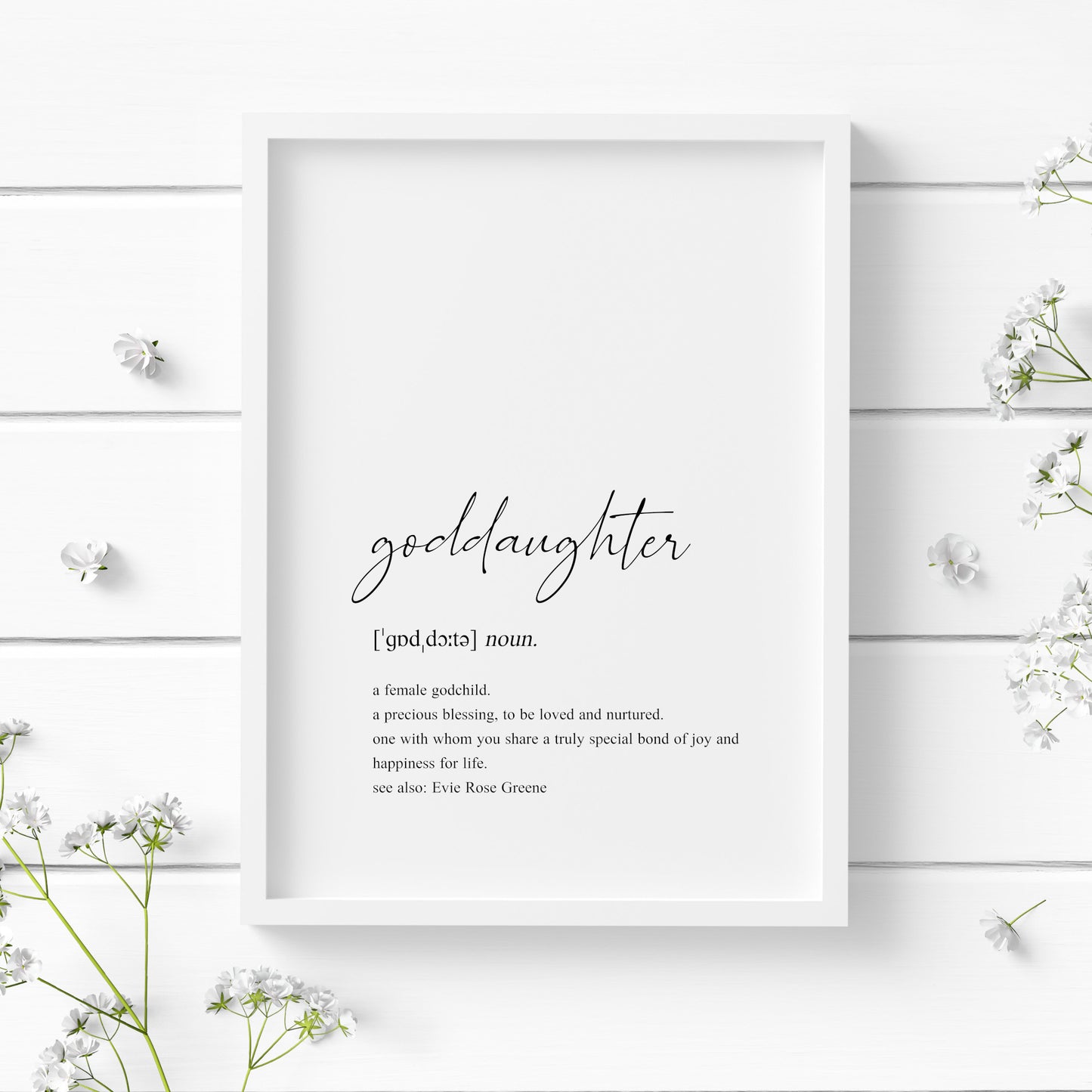 Single portrait typography print showing a dictionary style definition of the word goddaughter. The word goddaughter is in a modern script font, with the remaining text in a lower case serif font. The print is personalised with the name of the goddaughter in a "see also:" section at the end of the definition. Text is black on a white background.