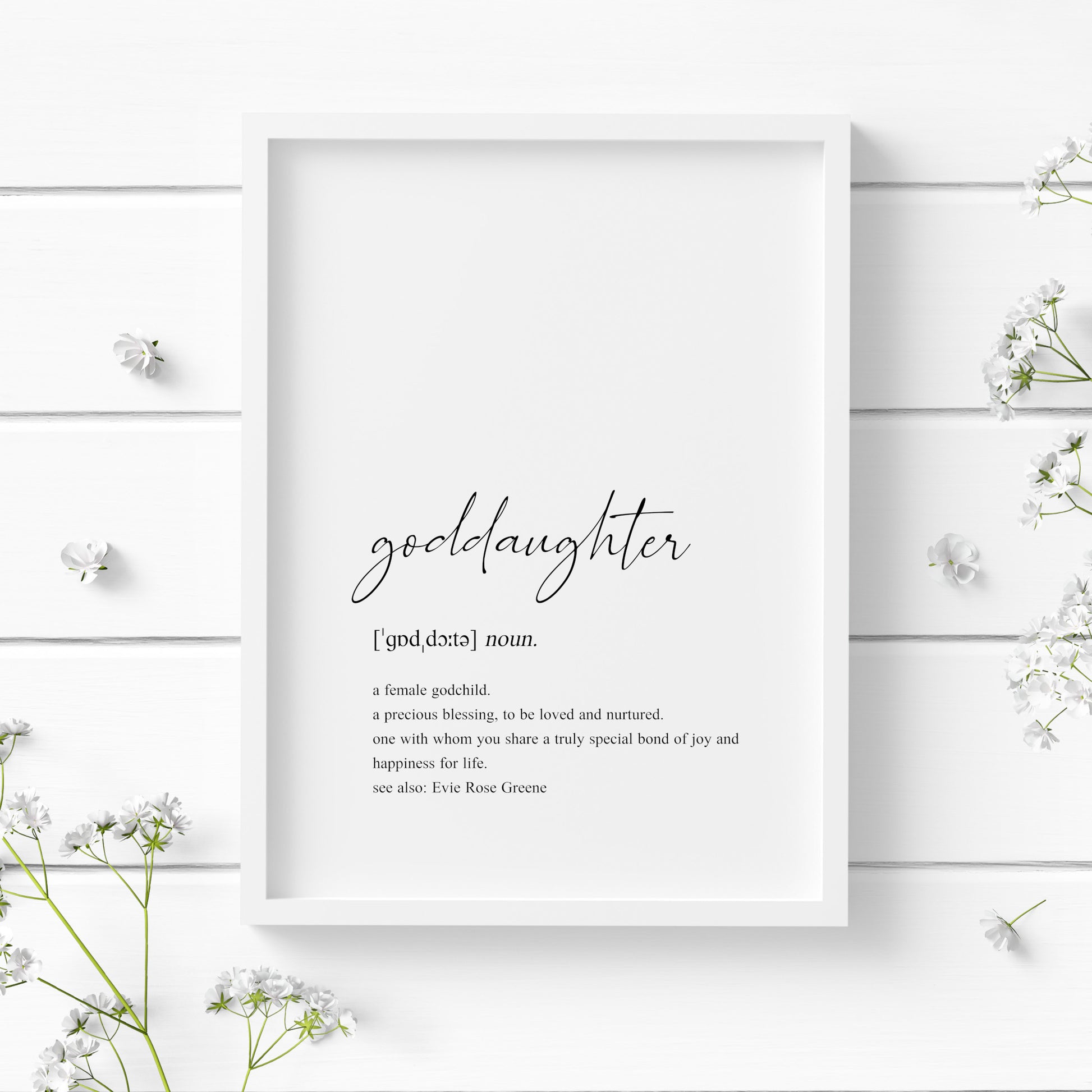 Single portrait typography print showing a dictionary style definition of the word goddaughter. The word goddaughter is in a modern script font, with the remaining text in a lower case serif font. The print is personalised with the name of the goddaughter in a "see also:" section at the end of the definition. Text is black on a white background.
