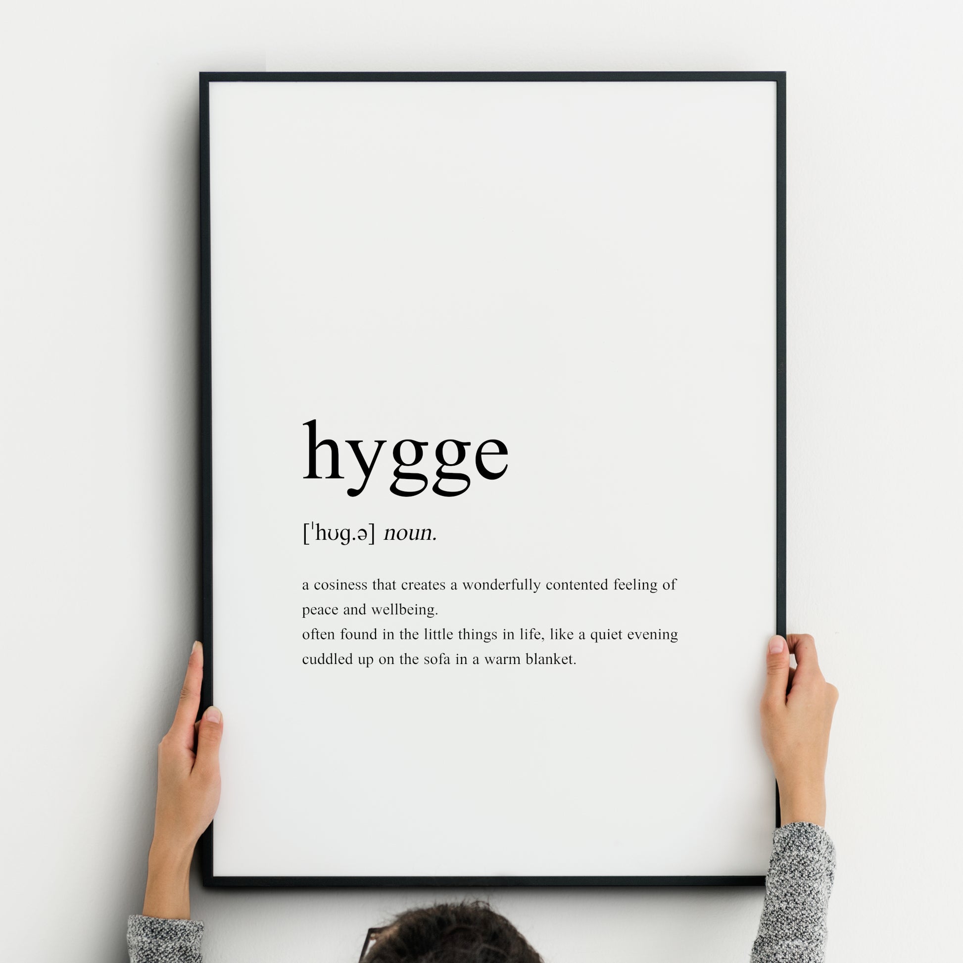 Single portrait typography print featuring a dictionary-style definition of the word hygge. It includes the word itself, pronunciation, type and definition. Text is in a lower case serif font, left-aligned and black on a white background.
