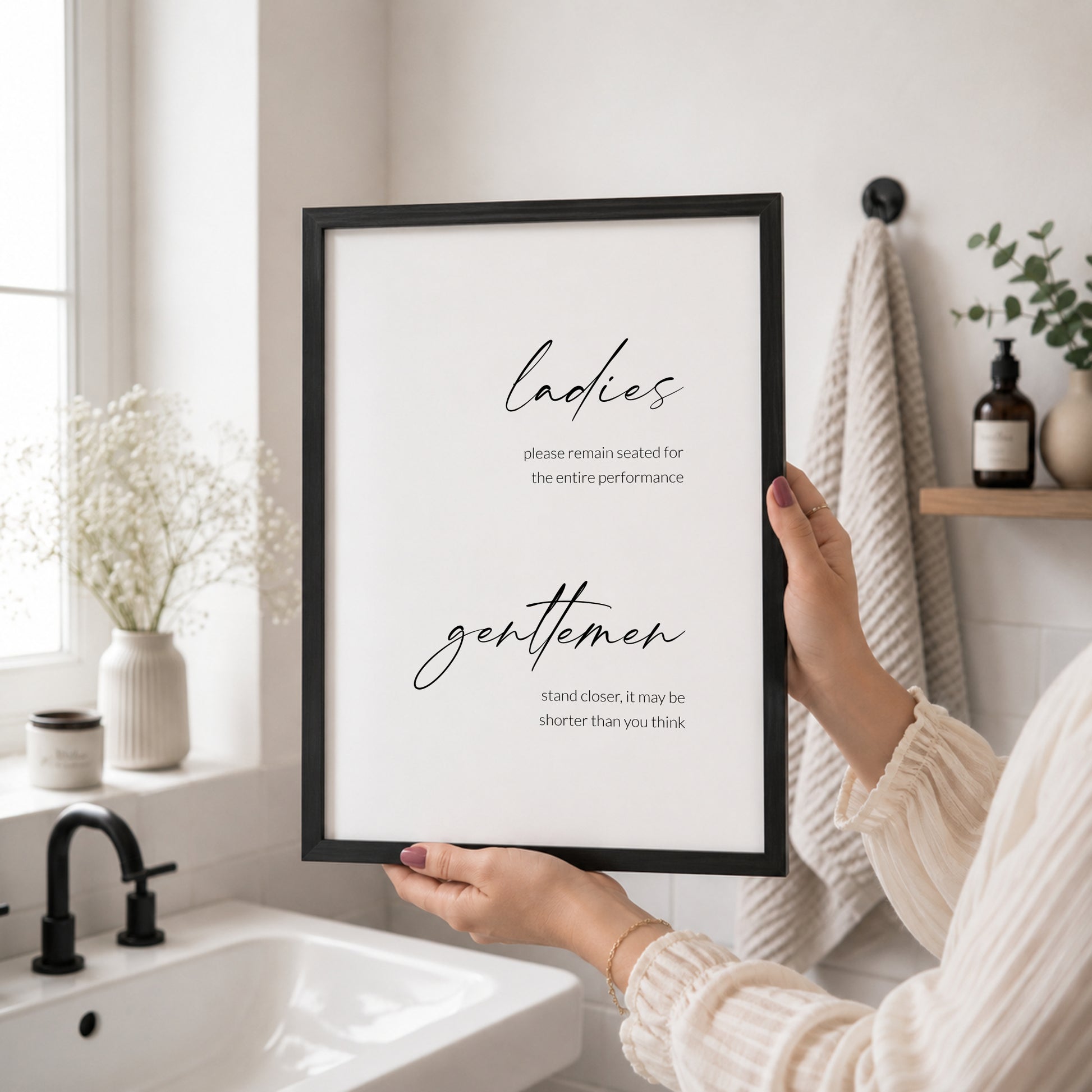 Minimalist funny bathroom typography print with “ladies” in large black script above smaller right-aligned text reading “please remain seated for the entire performance”, and “gentlemen” in large script above right-aligned text reading “stand closer, it may be shorter than you think”, on a white background.