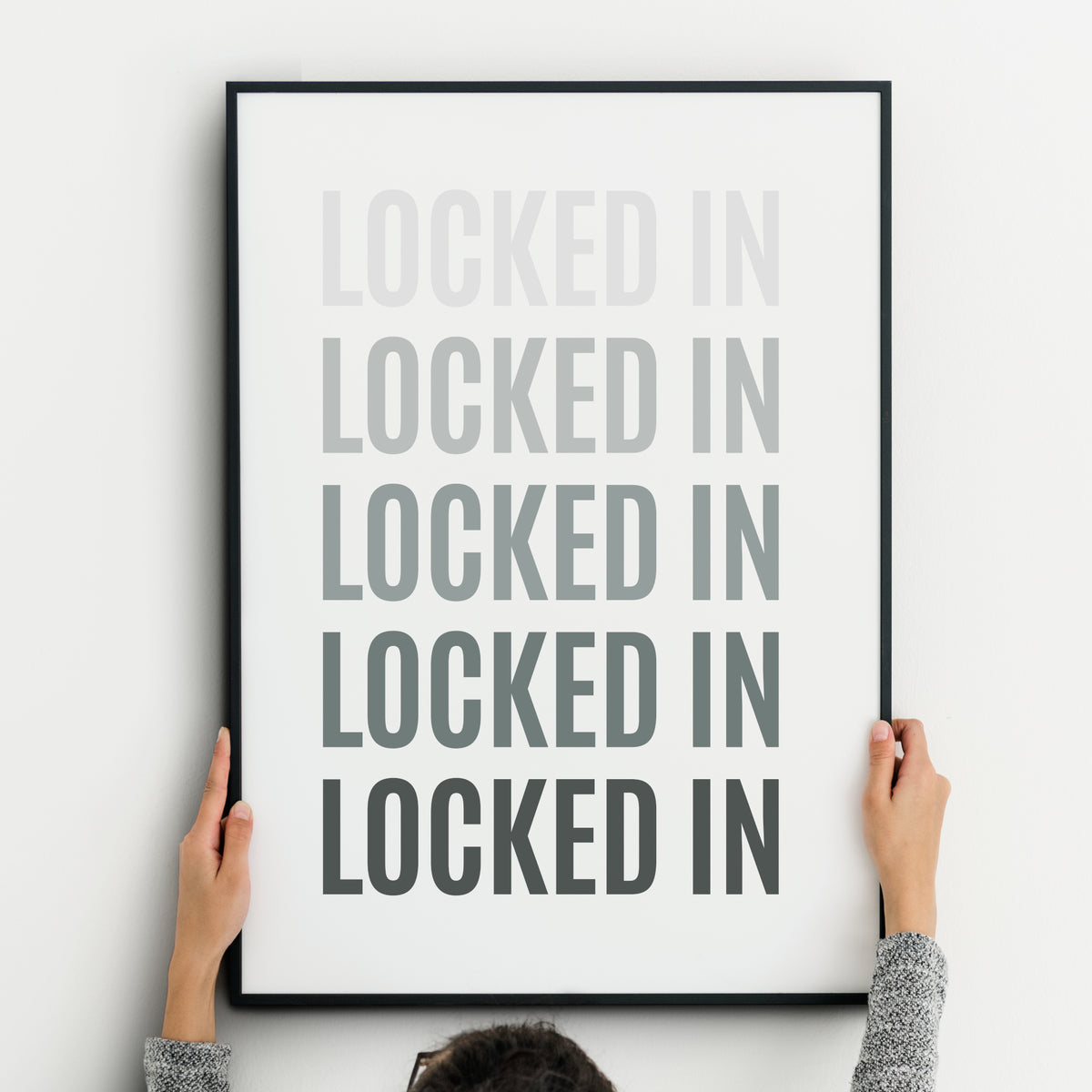 Locked In motivational typography print  featuring the words "LOCKED IN" repeated five times in bold uppercase lettering. The text progresses from pale to increasingly deep shades of grey, creating an affirmation-inspired design representing growing focus, commitment and determination.